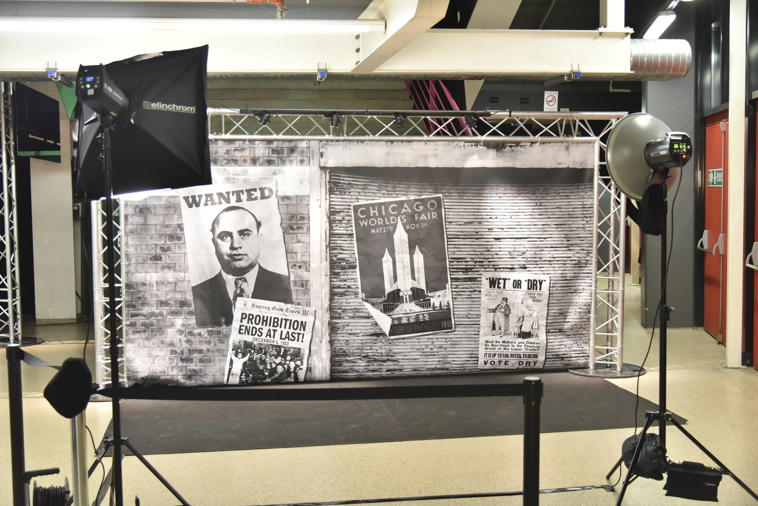 Décor noir et blanc avec des affiches vintage représentant un homme recherché, une foire mondiale de Chicago et une campagne pour le vote en faveur de la prohibition.