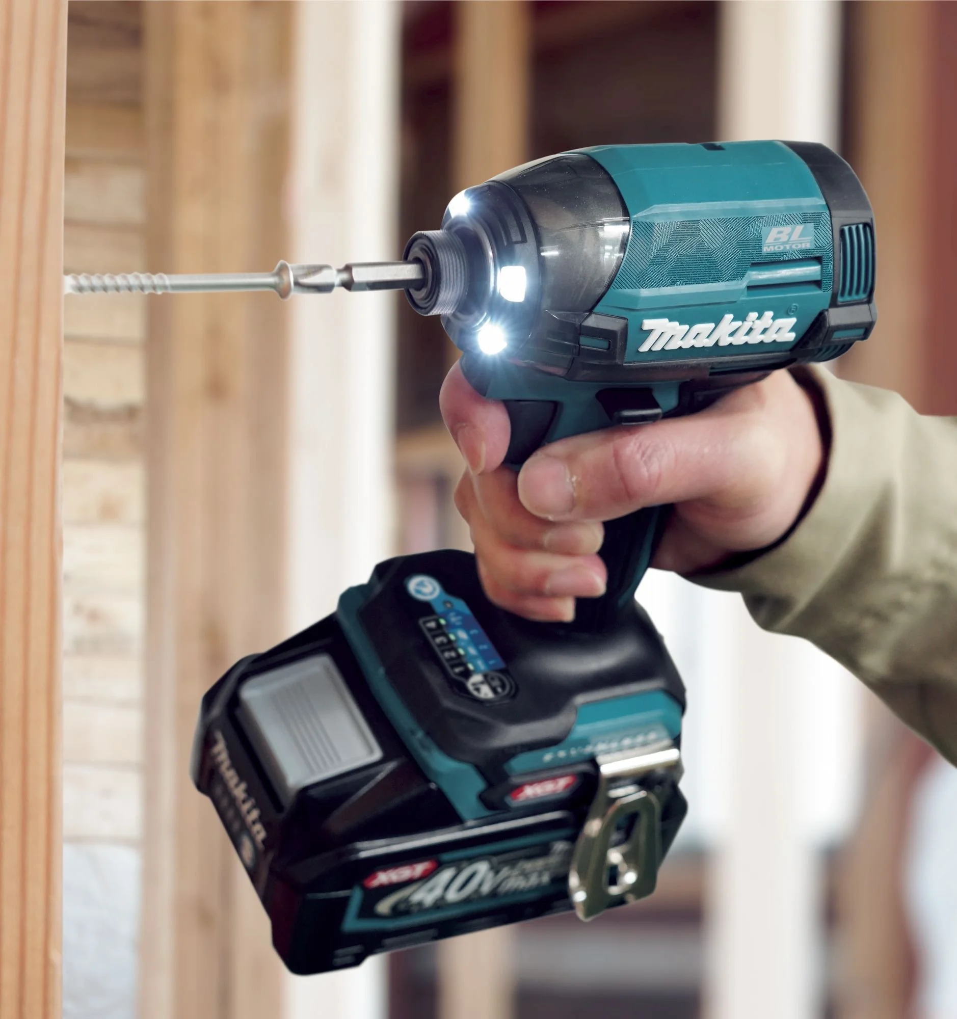 Person using a cordless Makita drill to screw into wood during a construction project.