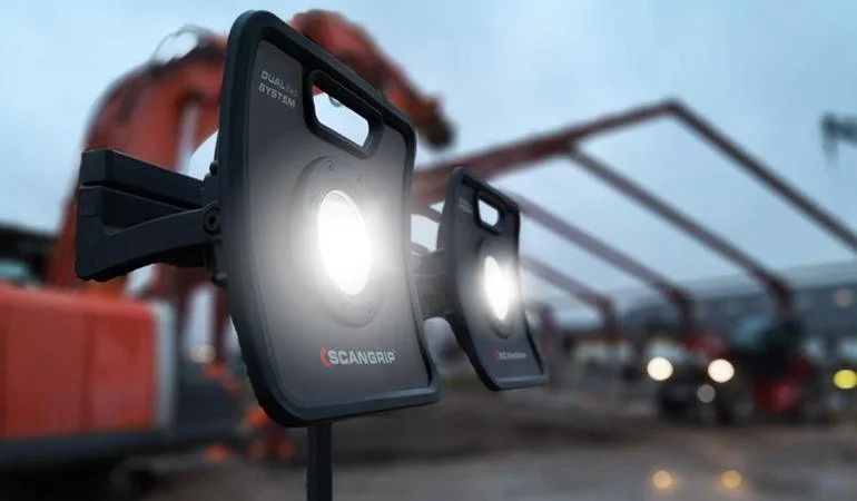Two handheld scanners used for truck bed scanning, with a construction site in the background.