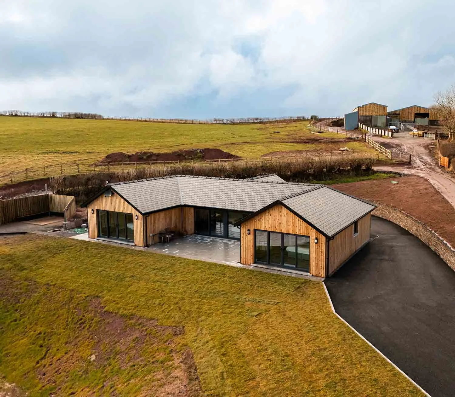 An aerial, high-angle photograph of one of Beacons View's luxury lodges, nestled in the lush, rolling countryside of the Brecon Beacons, Wales.