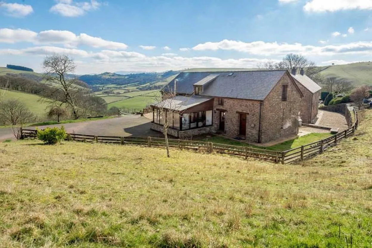 External view of Beacons View farm holiday cottages surrounded by farmland, with Brecon Beacons view in the background.