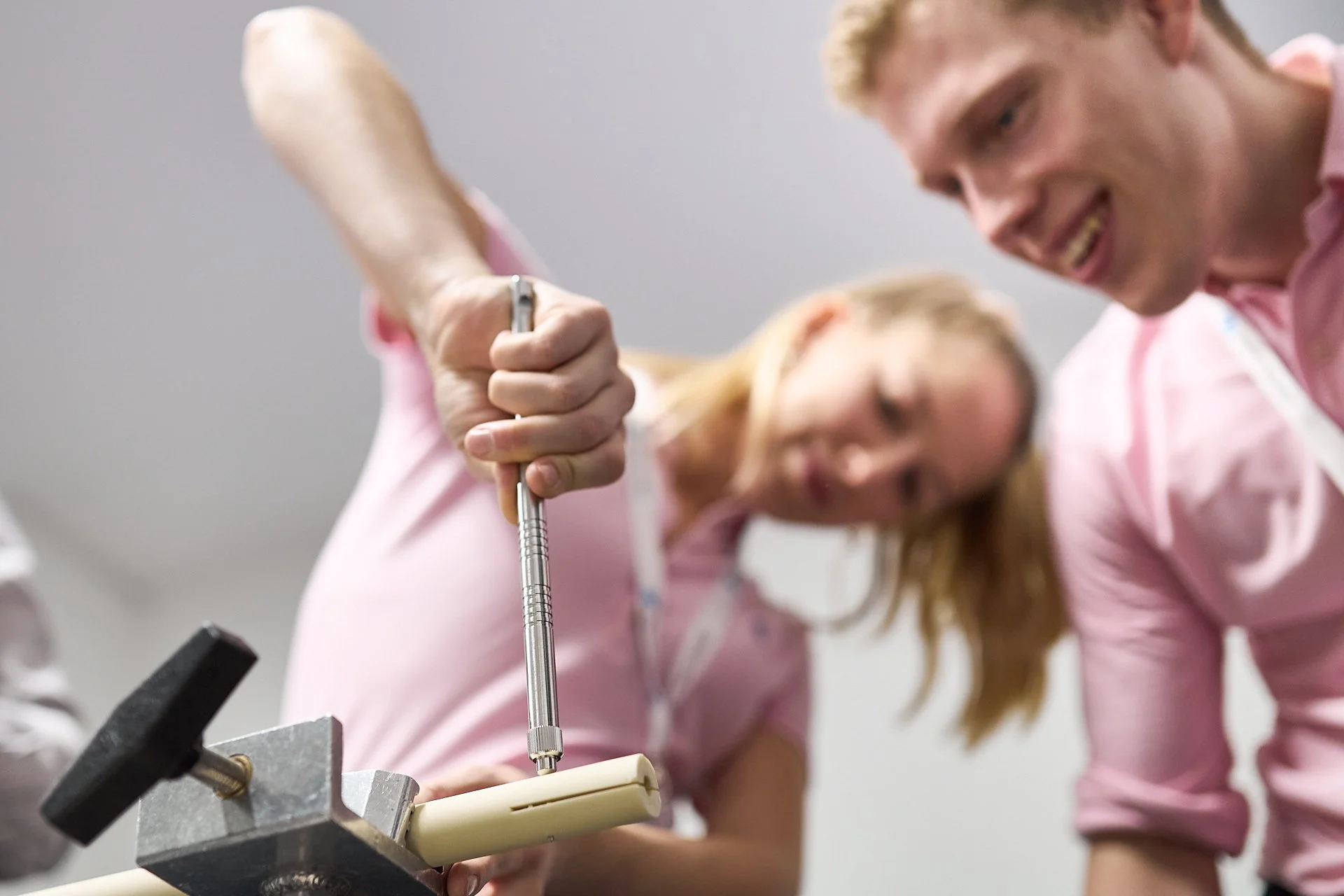Zwei Personen in Pink-Kleidern arbeiten an einem technischen Projekt mit einem Schraubenzieher.