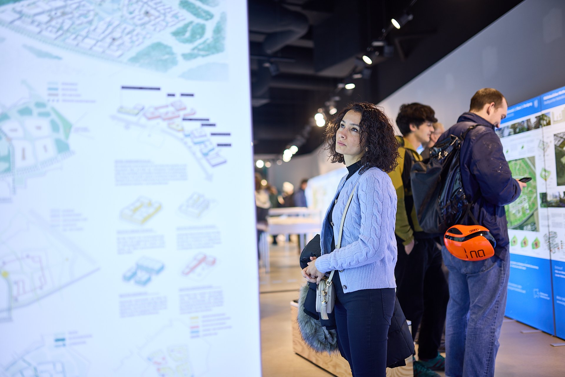 Menschen betrachten Stadtpläne und Visualisierungen auf Ausstellungen oder Messen.