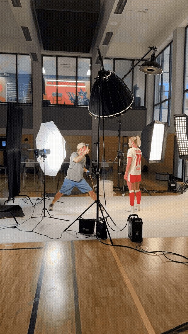Fotostudio mit Fotograf und einem Kind in einem Sporttrikot, die für ein Fotoshooting posieren, mit professioneller Beleuchtung und Kameraequipment