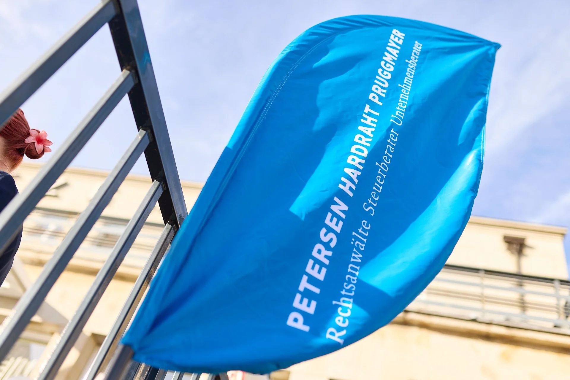 Blaue Flagge mit weißen Texten, die politische Partei oder Organisation repräsentiert, hängt an einem Zaun in der Stadt.