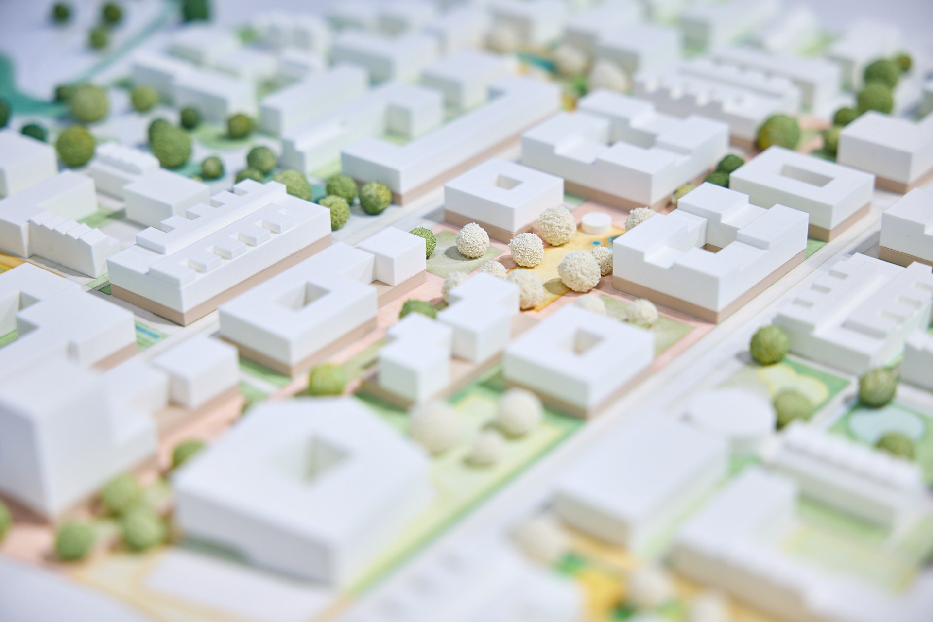 Architektonisches Modell eines Wohngebietes mit weißen Gebäuden, Bäumen und Grünflächen.