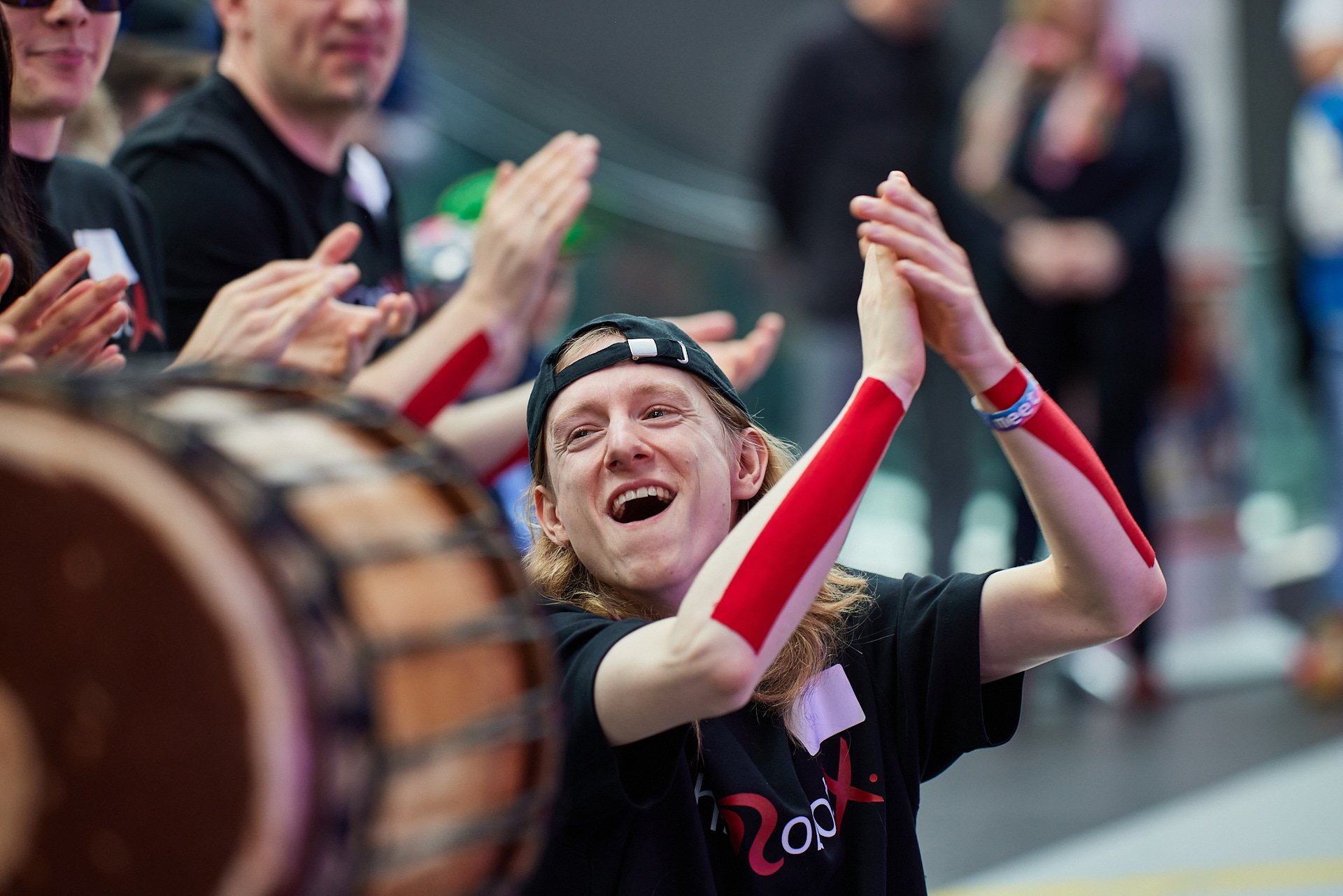 Jugendlicher freut sich mit erhobenen Armen und im Hintergrund klatschende Freunde beim Sportereignis.