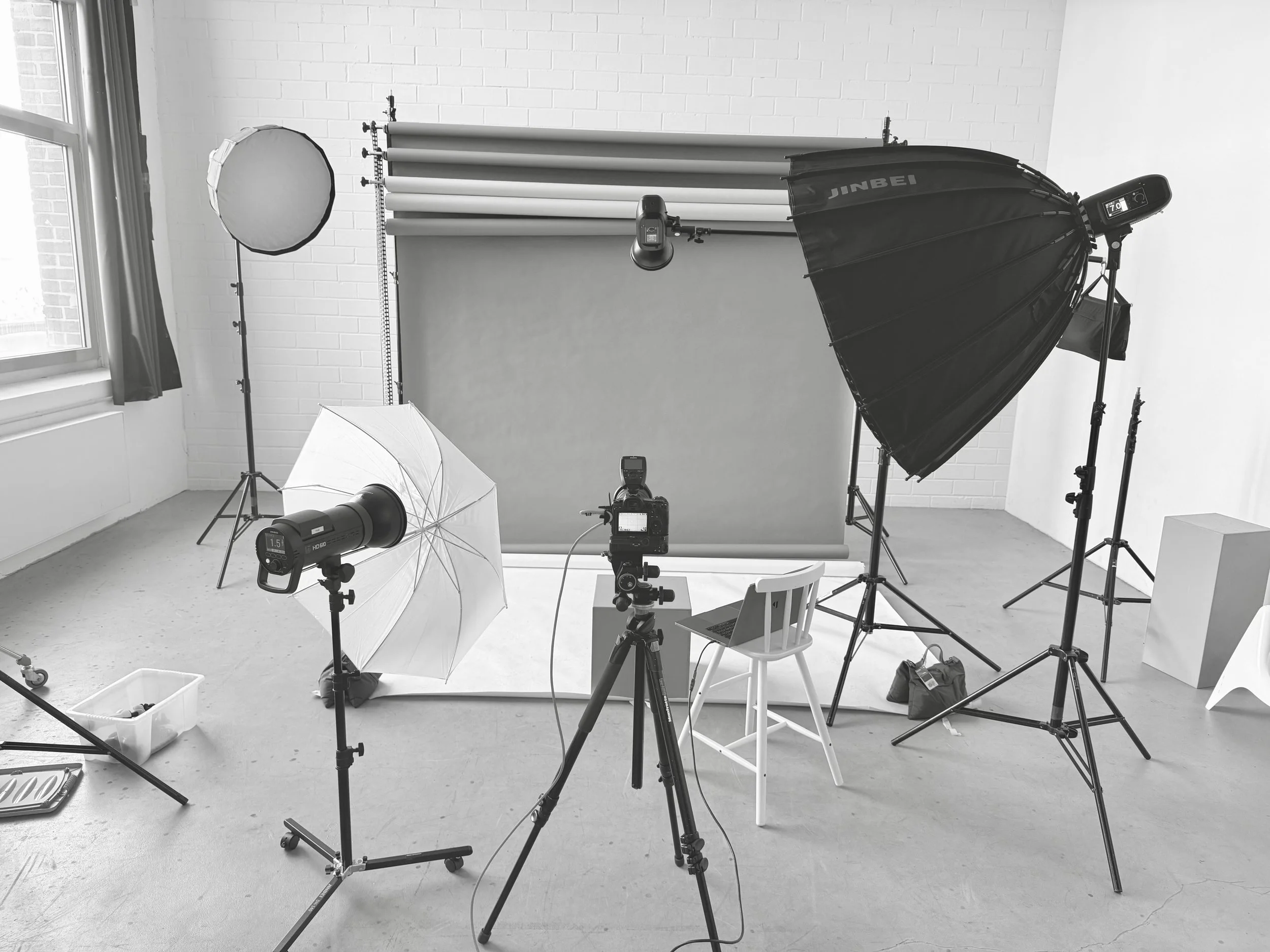 Fotostudio mit professioneller Beleuchtung, Hintergrund und Kamera auf einem Stativ.