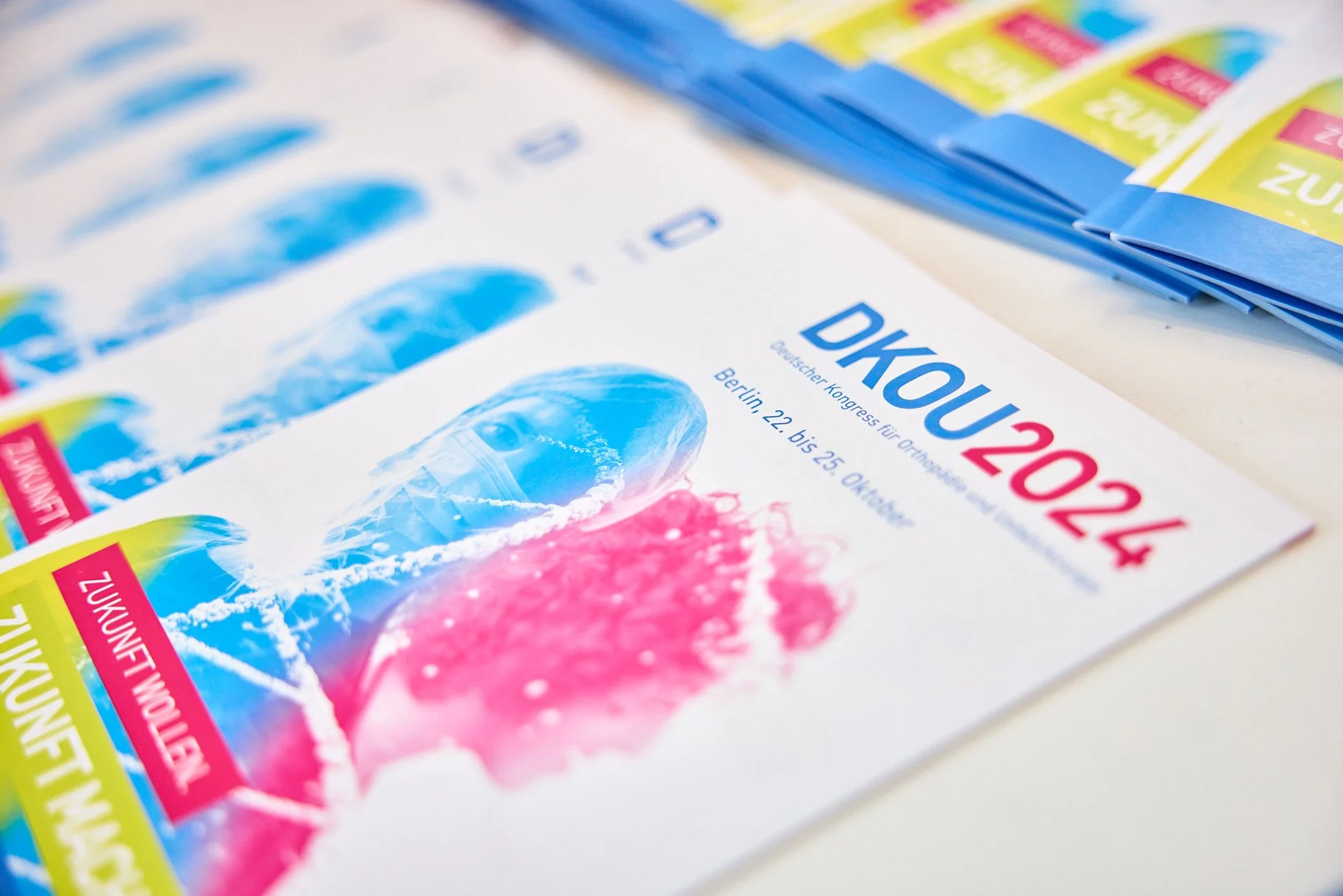 Flyer für den Deutschen Kongress für Orthopädie 2024, der vom 22. bis 25. Oktober in Berlin stattfindet, mit bunten Farbüberblendungen und Text.