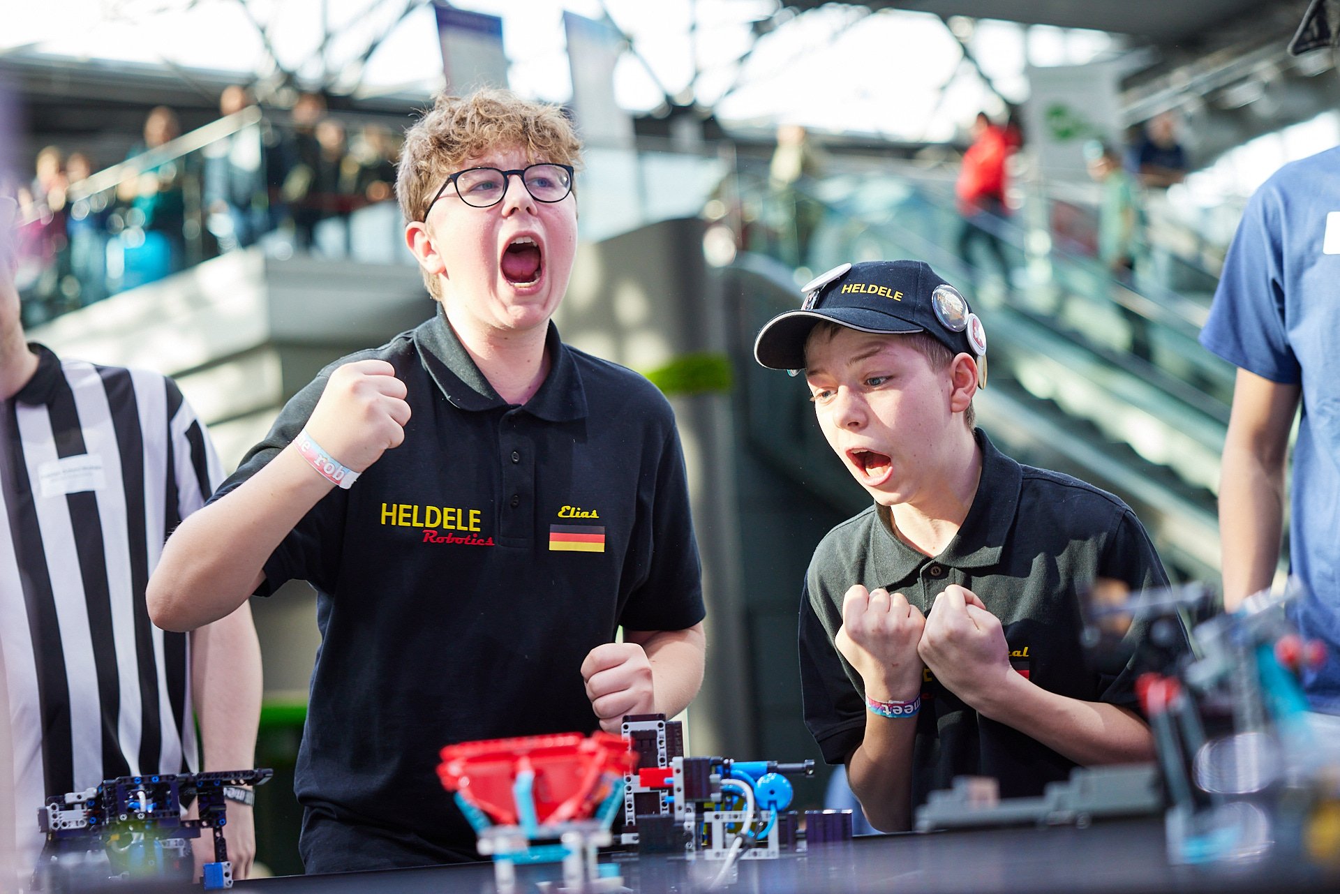 Zwei Jugendliche, die sich in einem Robotik-Wettbewerb befinden, jubeln und feiern.