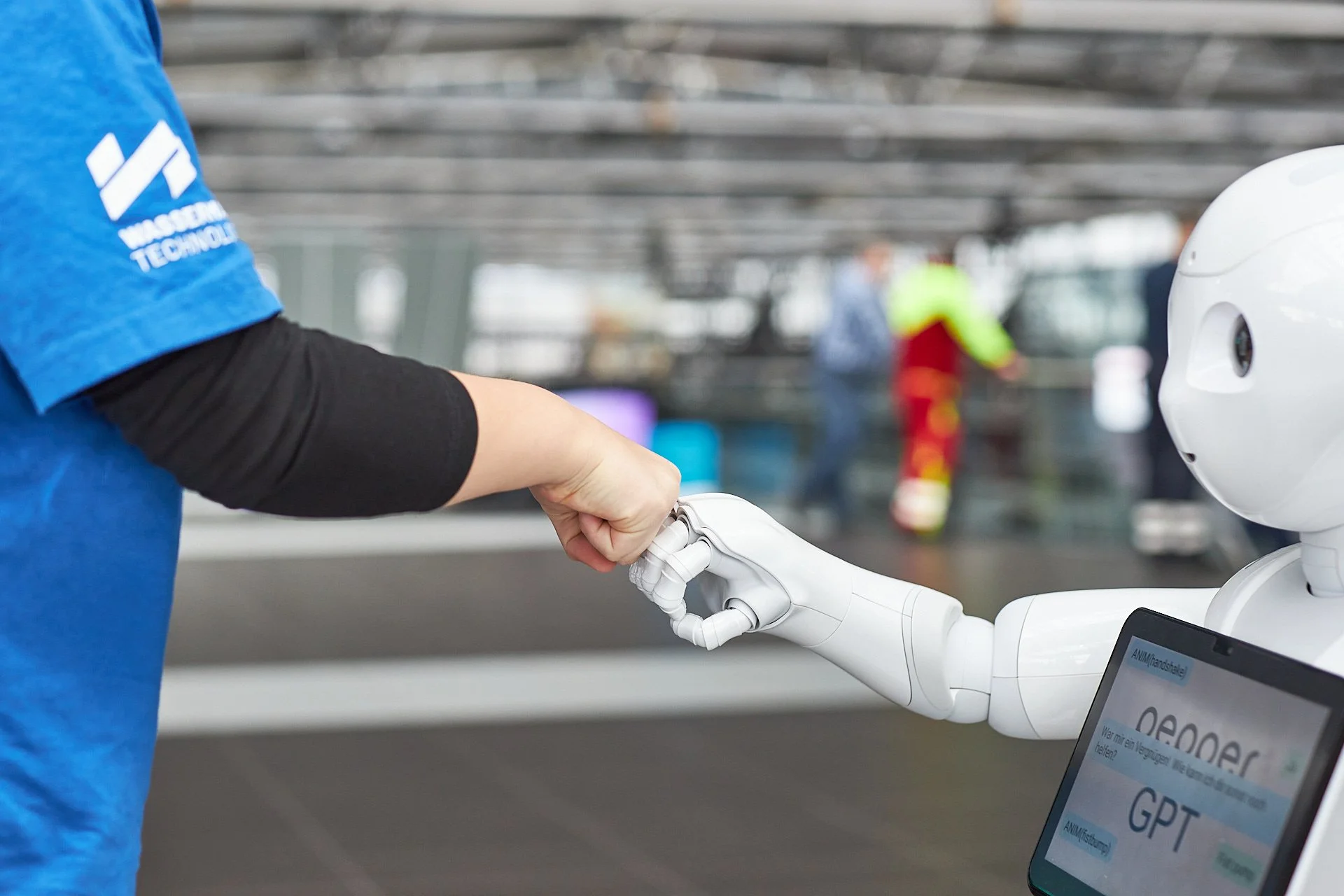 Ein humanoider Roboter schüttelt die Hand eines Menschen in einem modernen Gebäude.