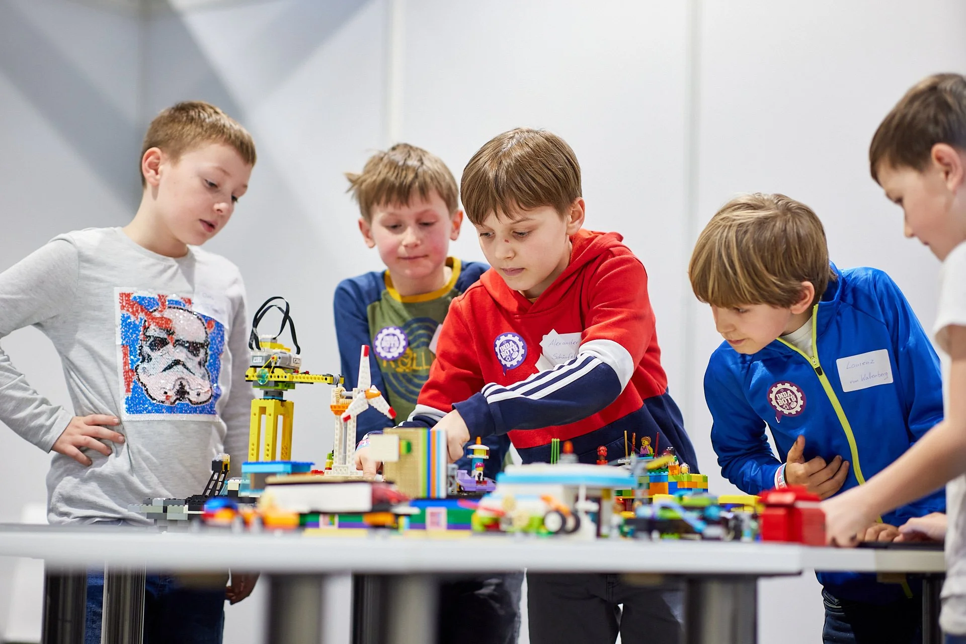 Eine Gruppe von fünf Jungen betrachtet zusammen eine große Lego-Stadt auf einem Tisch.