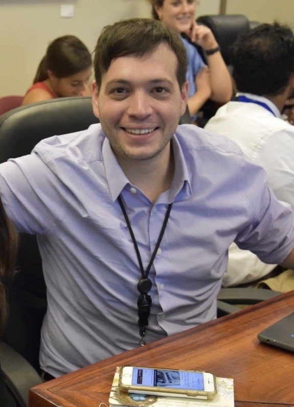 A man with short, dark hair wearing a white shirt.