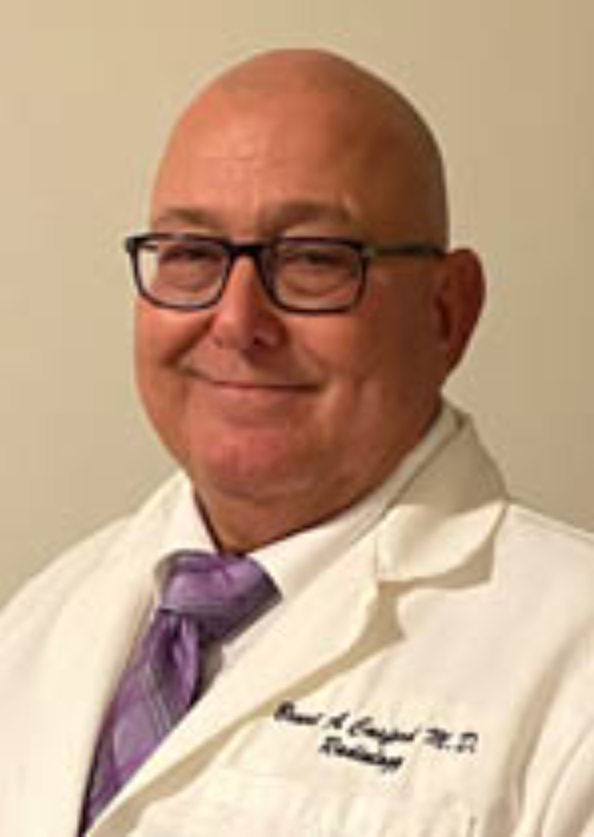 A middle-aged man with glasses, bald head, wearing a white lab coat and purple tie, smiling at the camera.