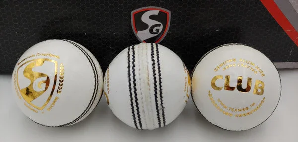 Three white golf balls with black and gold markings, placed on a black surface with a shield-shaped logo above them.