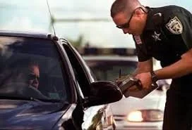A police officer issuing a ticket to a driver inside a black car. Jacob Fisher is the attorney to call!
