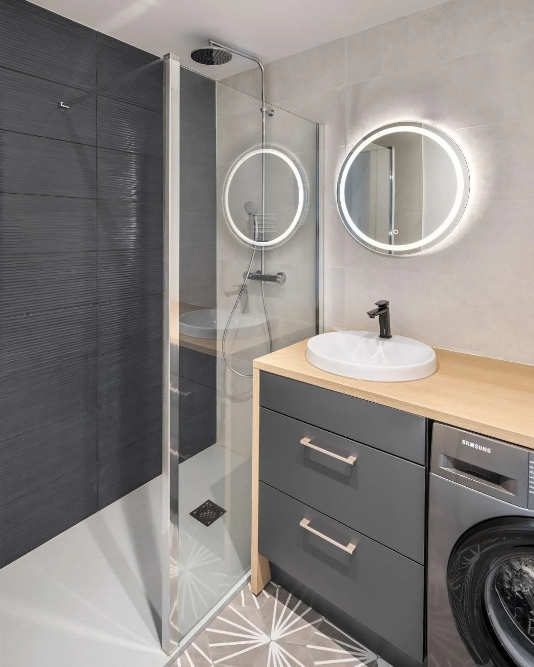 Salle de bains moderne,douche avec grand receveur extra plat. Miroir rond Led, plan de travail décor bois, vasque semi-encastrée. Design sobre, minimaliste pour location locative.