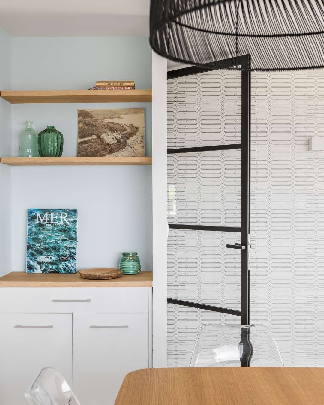 Aménagement coin repas avec verrrière tout hauteur esprit atelier loft. Etagères en bois sur mesure. Expertise en optimisation de petits espaces. 