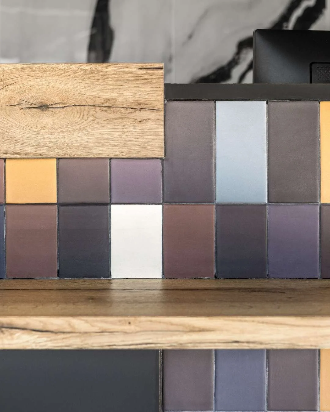 Gros plan sur le calepinage de carreaux Mutina. Association de texture bois faïence, et mélaminé noir.