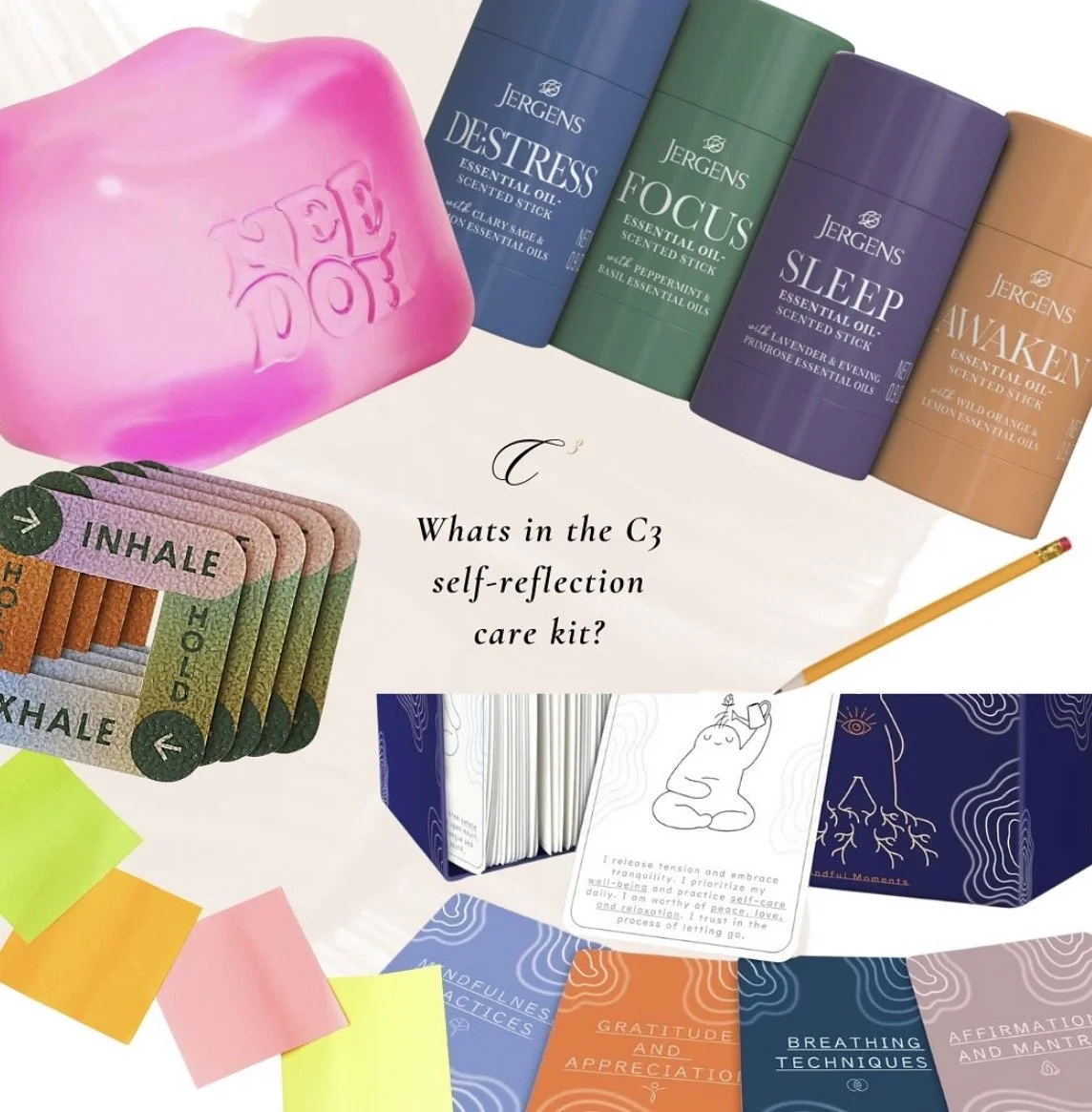 Self-reflection care kit consisting of essential oil sticks labeled 'Detress', 'Focus', 'Sleep', and 'Awaken'; colorful affirmation and mindfulness cards; a pink soap with the word 'LOVE' embossed; multicolored sticky notes; and various mindfulness and gratitude cards.