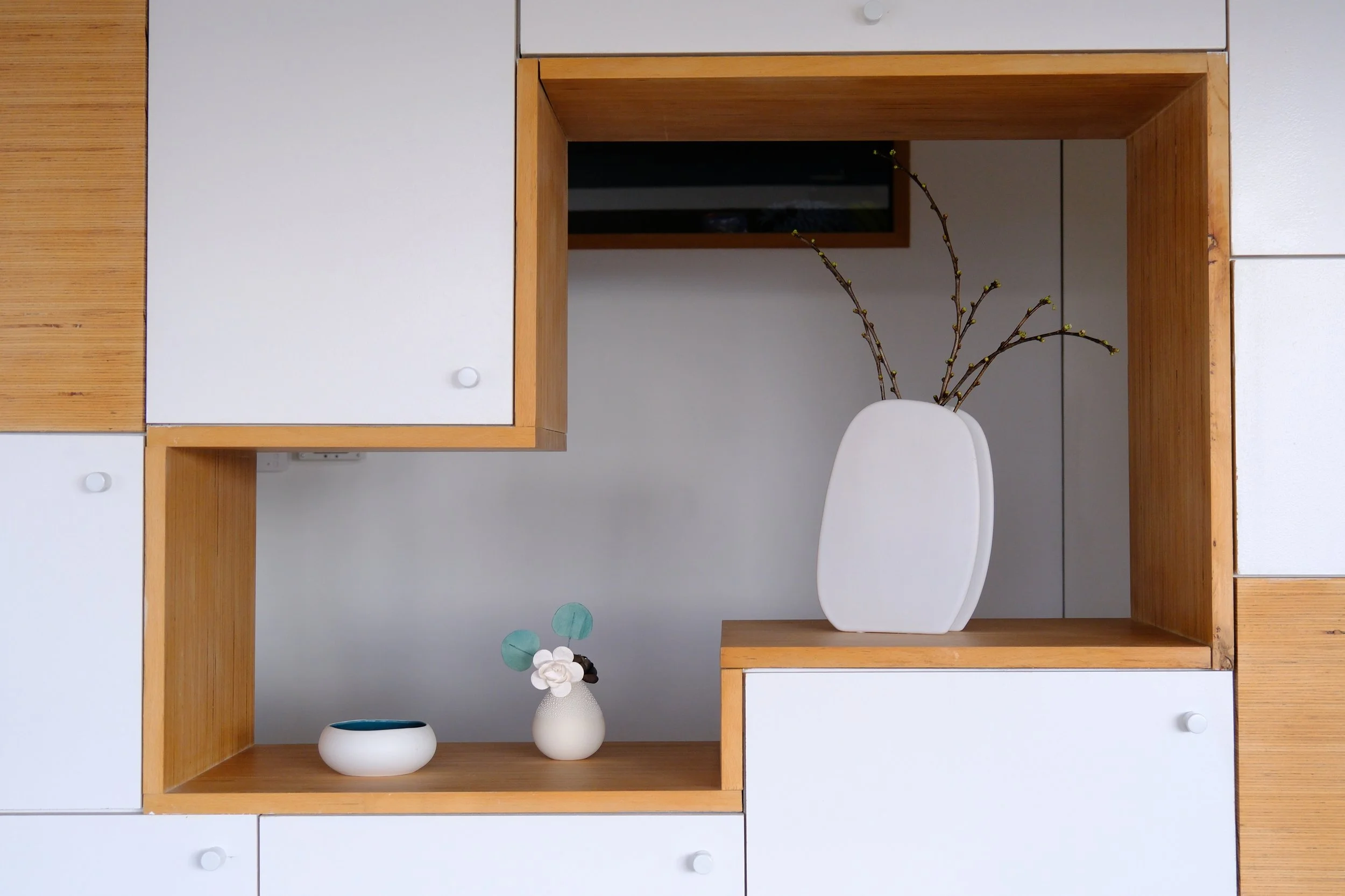 Vase blanc avec branches de fleurs, petite coupelle blanche avec intérieur bleu, petite plante dans un vase blanc, design minimaliste, rangement en bois et blanc