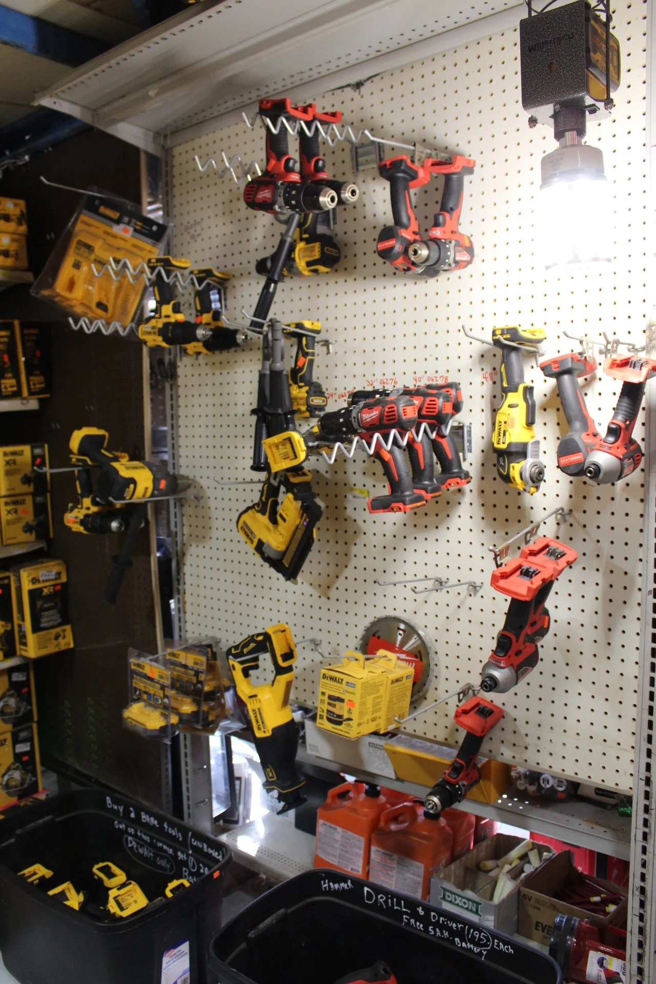 Power tools, including drills and saws, displayed on a pegboard and shelves in a hardware store.