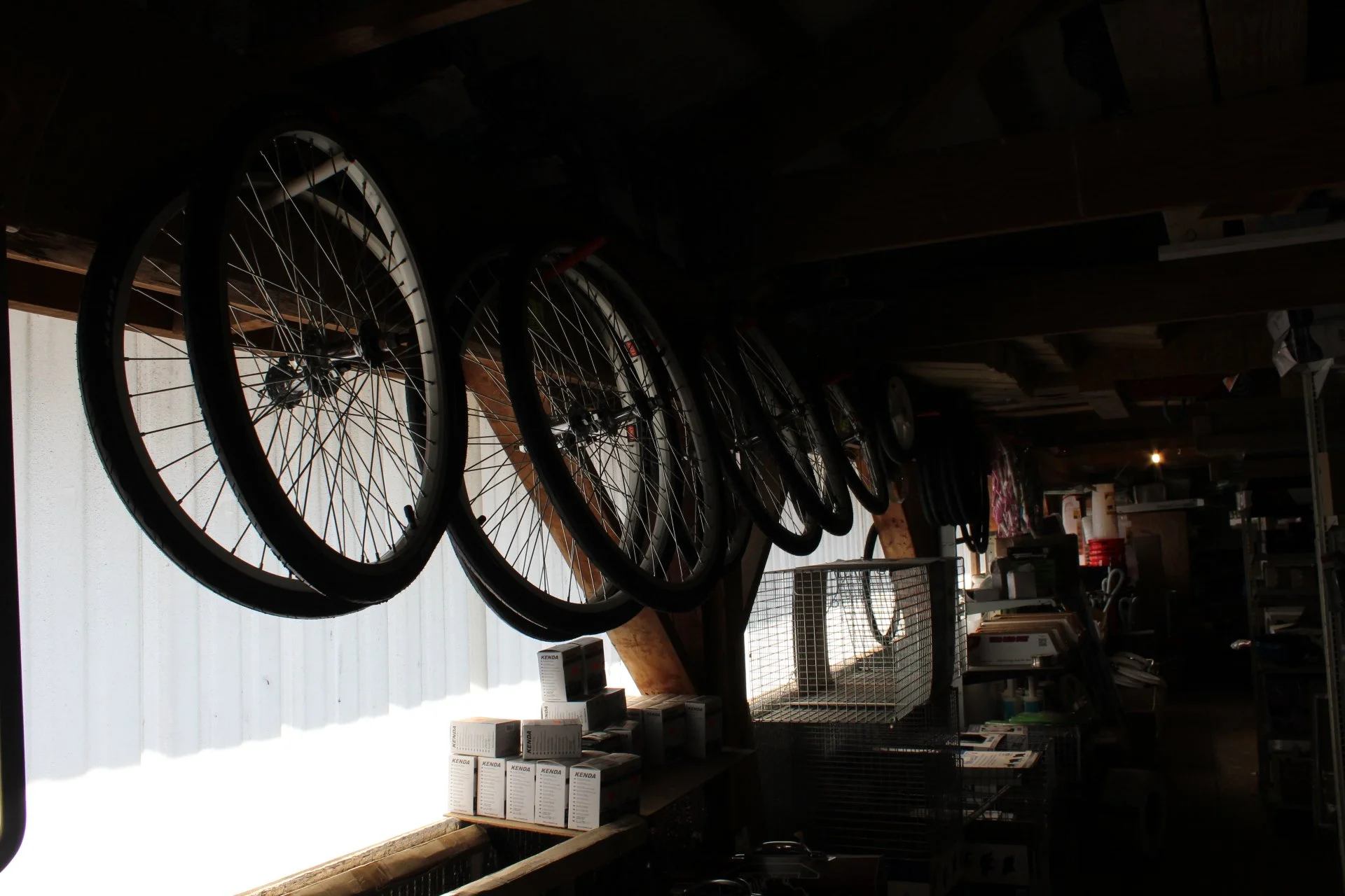 Bicycle wheels hanging upside down in a cluttered workshop or storage room.