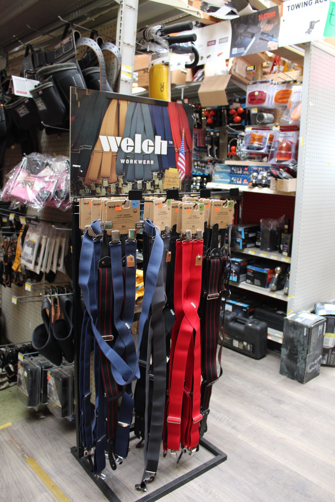 Display of workshop suspenders in a hardware store, with various tools and items on shelves in the background.
