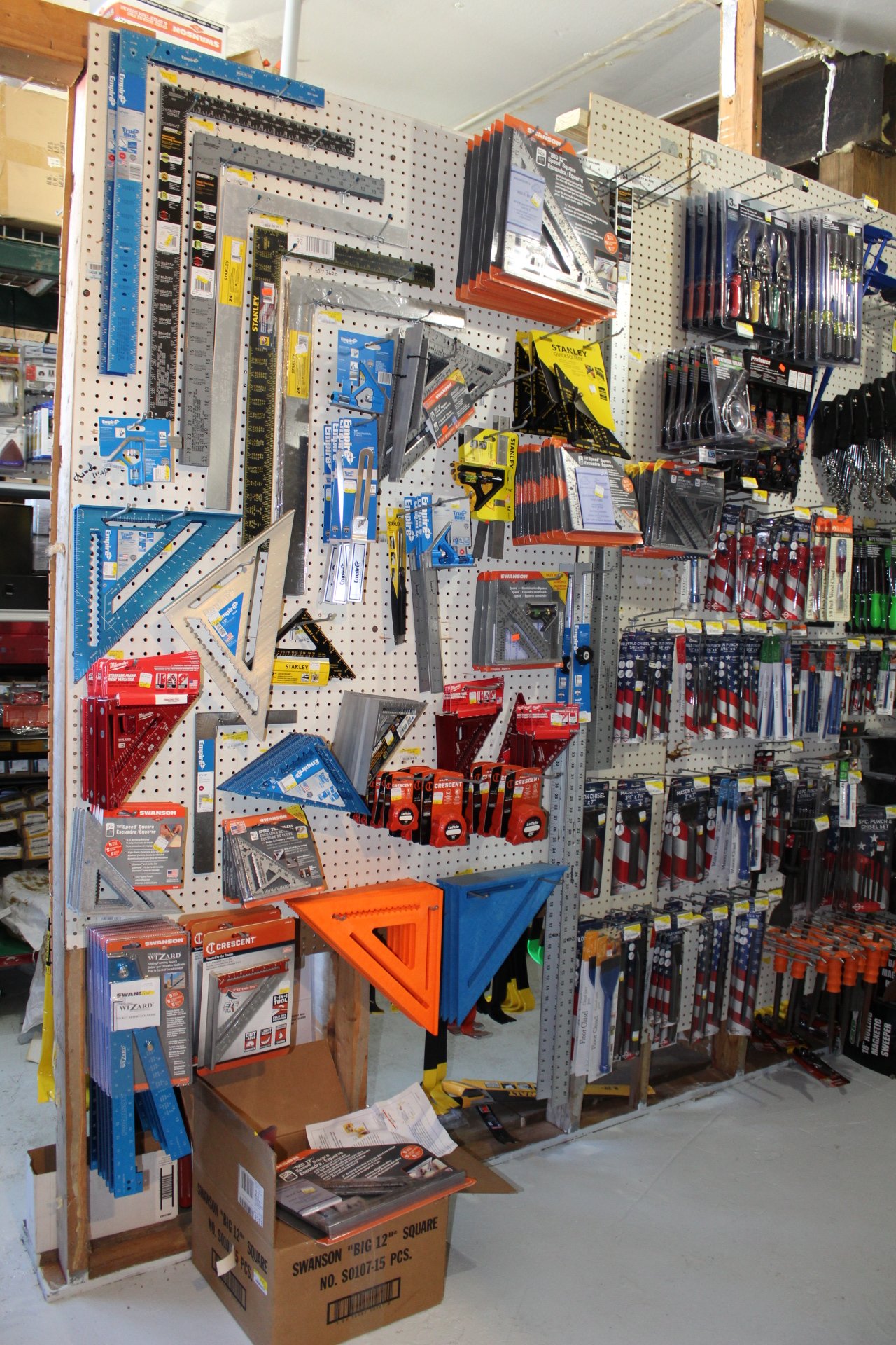 A pegboard display of various hand tools, rulers, squares, and measuring devices in a hardware store.