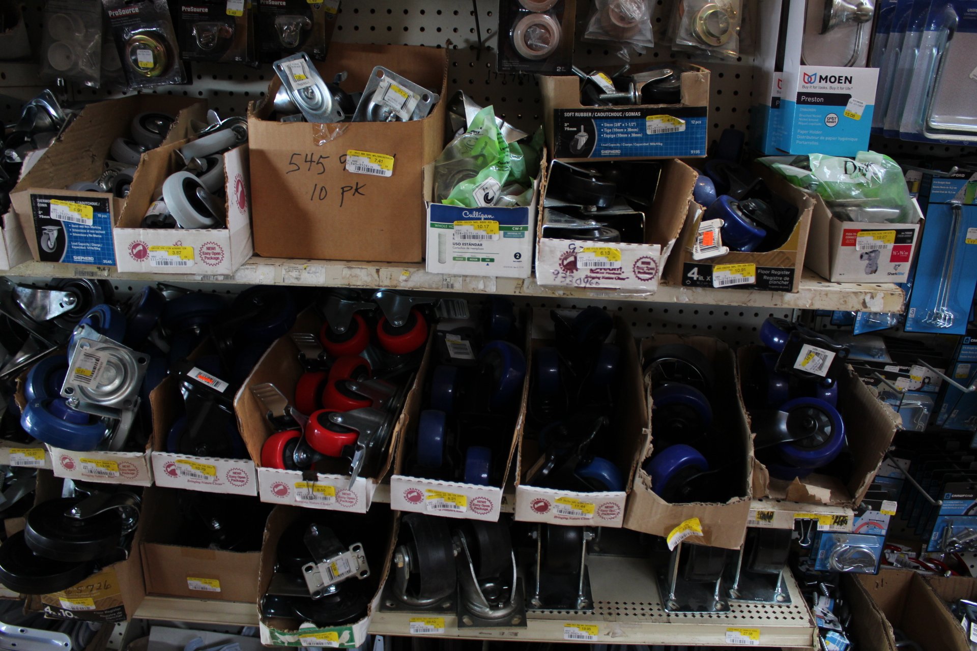 Store shelf with boxes and bins of caster wheels and hardware accessories.