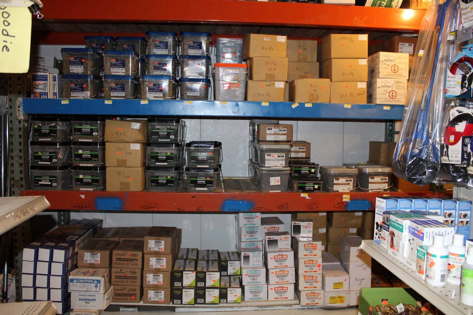 Shelf stocked with various boxes and containers of office or industrial supplies in a hardware or supply store.