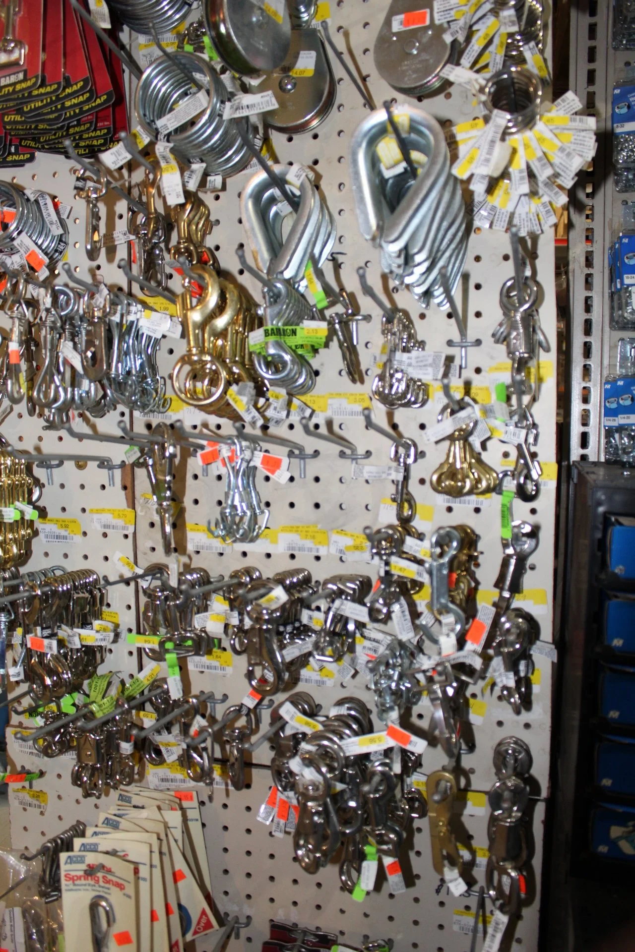 A display of metal hooks and hooks with weights hanging on a pegboard at a hardware store.