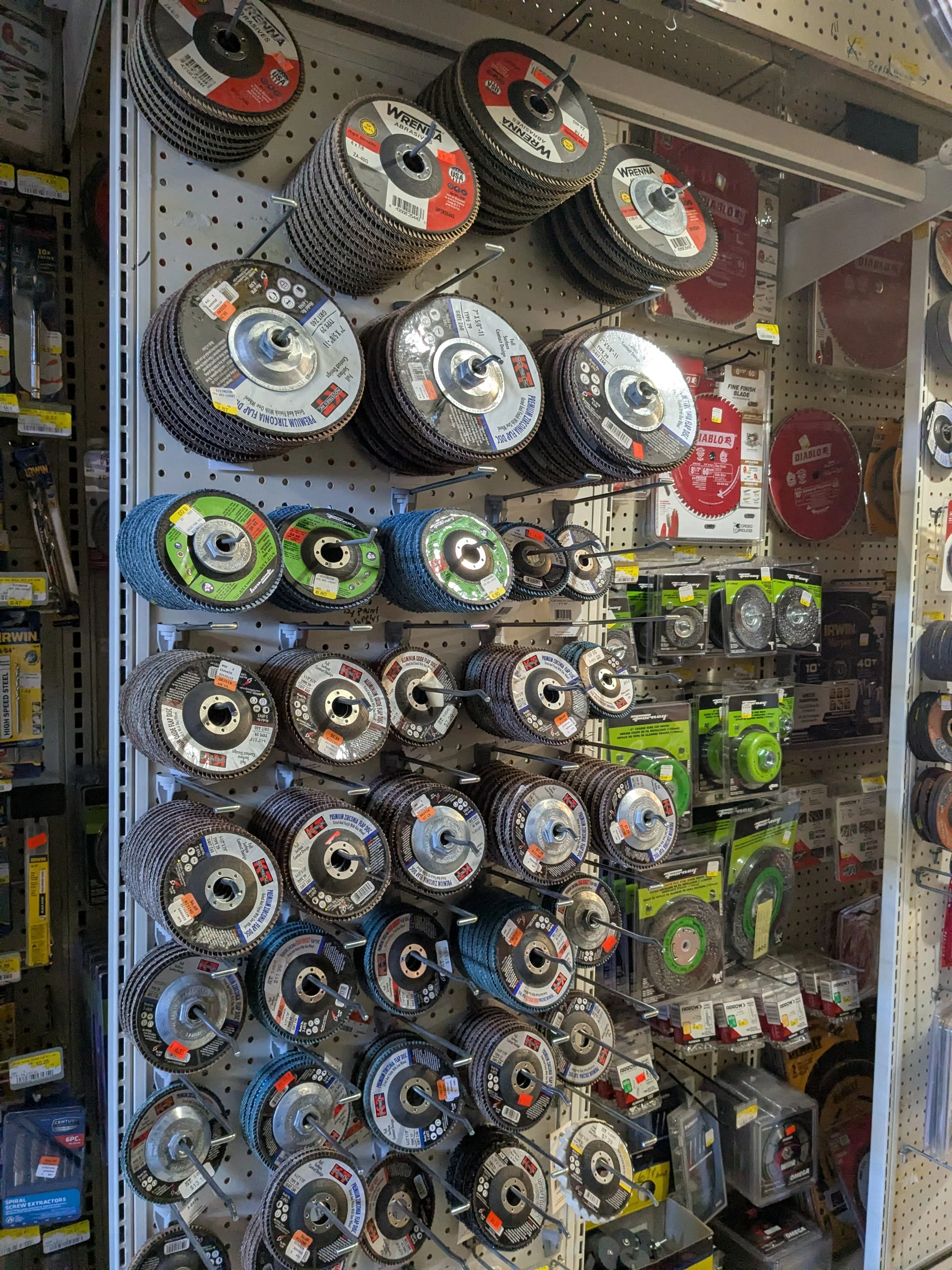A store display of grinding and cutting wheels for power tools, stacked on a pegboard wall.