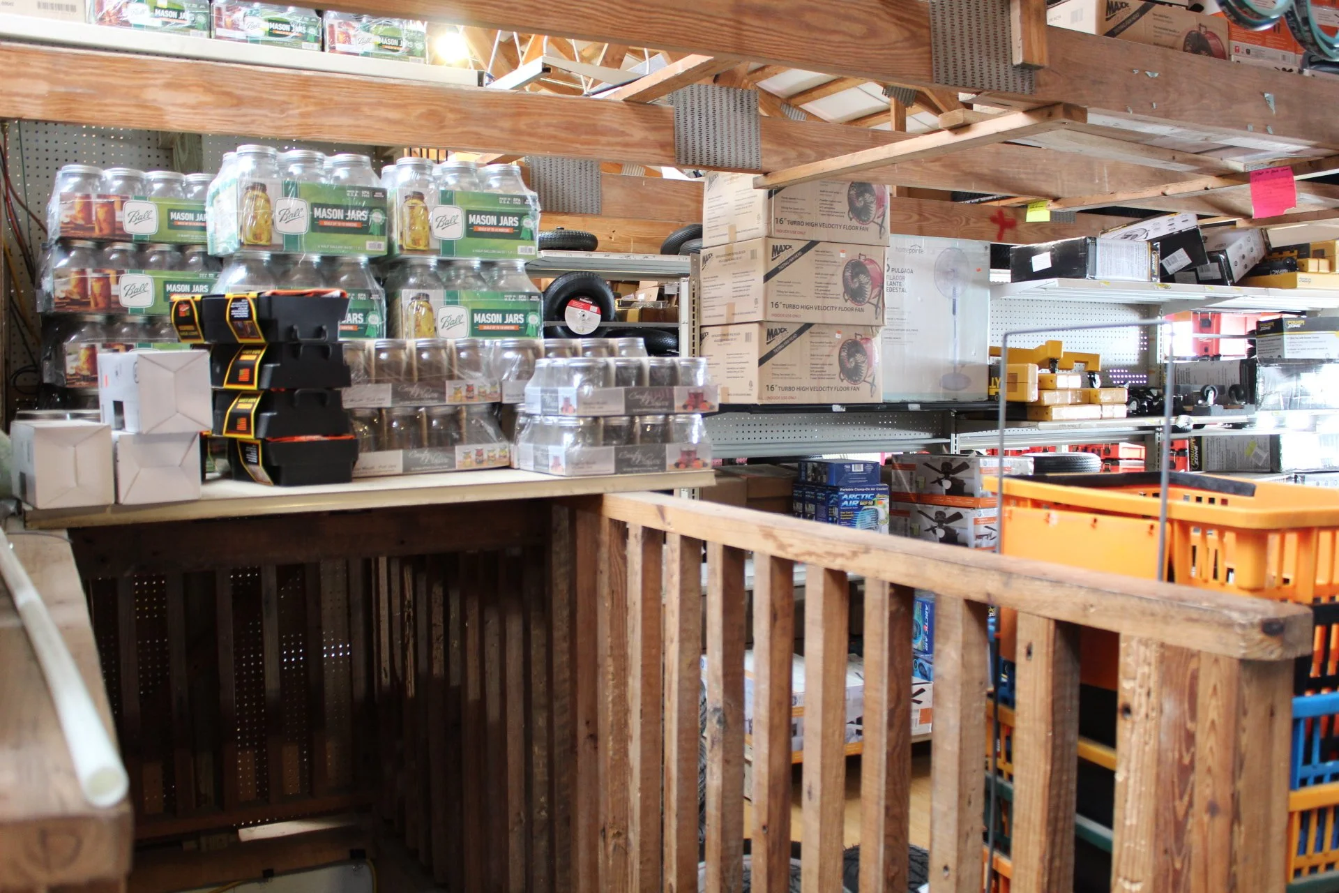 View of a storage area with shelves filled with boxes, jars, and tools, suggesting a workshop or hardware supply space.