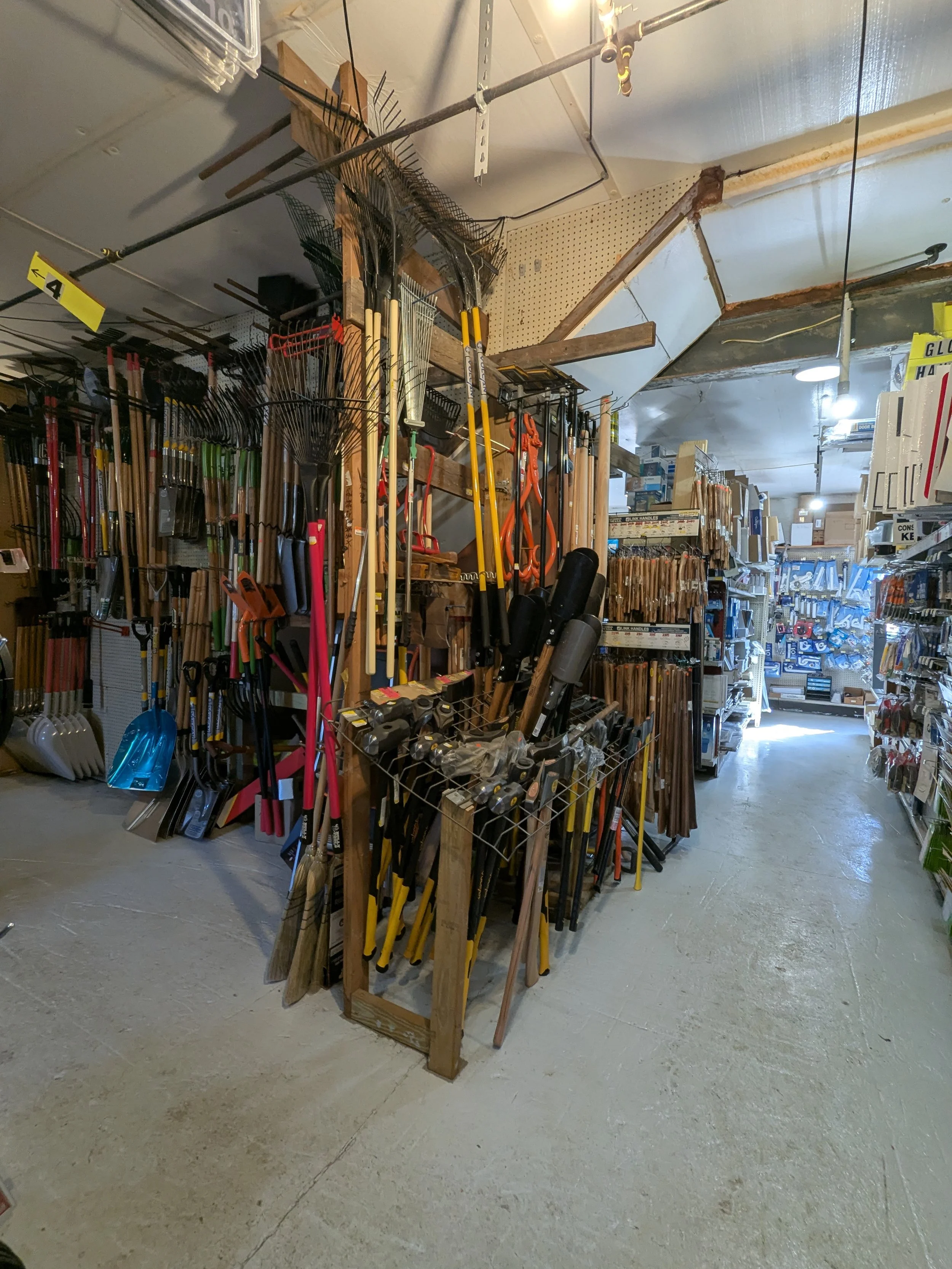 Tools on display in a hardware store, including shovels, rakes, hoes, and various gardening and landscaping tools.