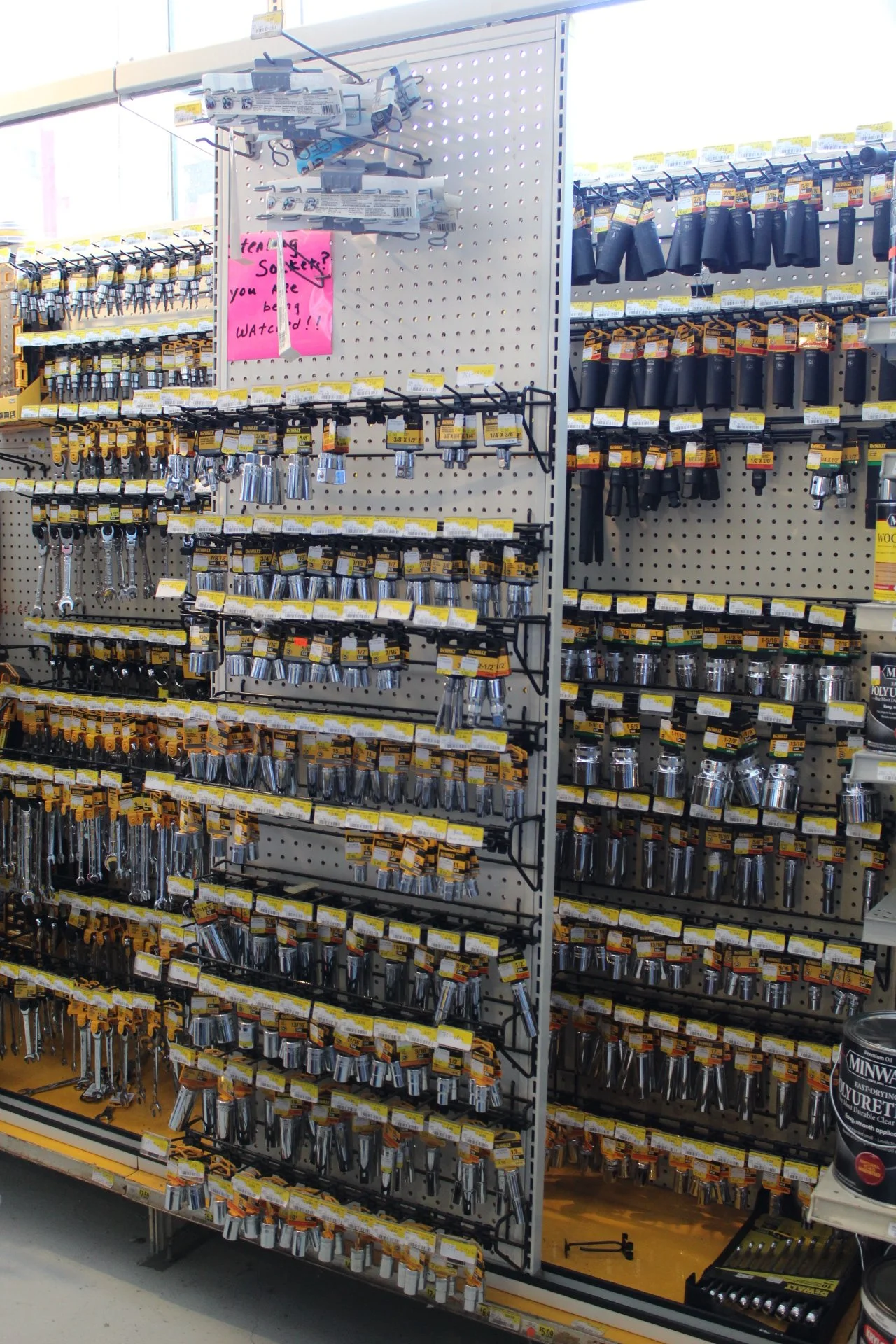 Tool display in a hardware store with socket wrenches, ratchets, and other hand tools organized on a pegboard shelving unit.