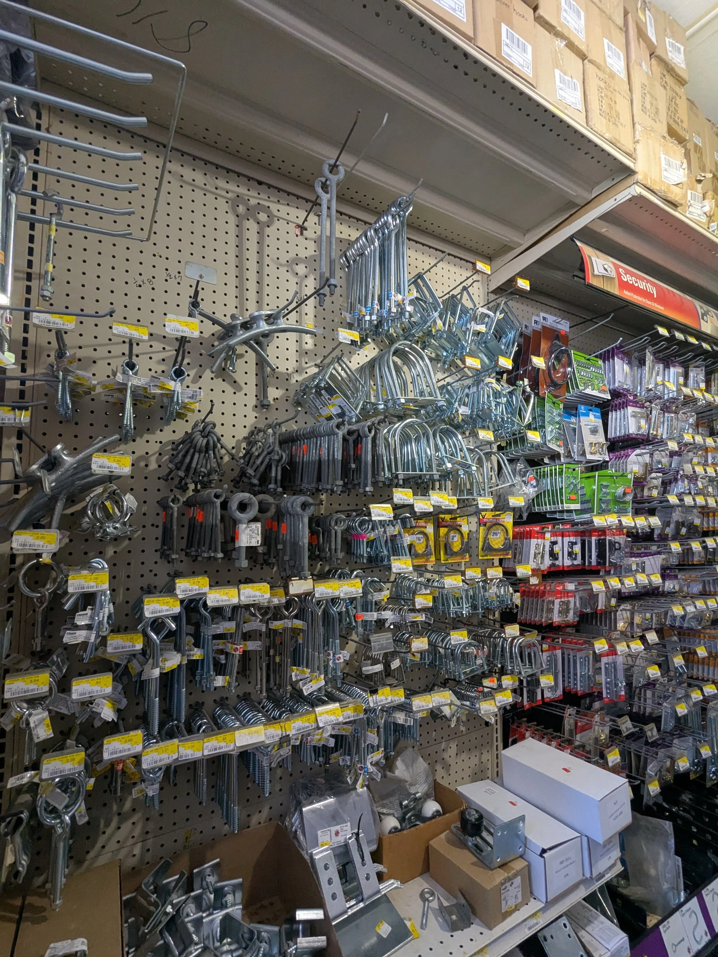 Hardware store shelf with various hooks, clamps, and hardware accessories.