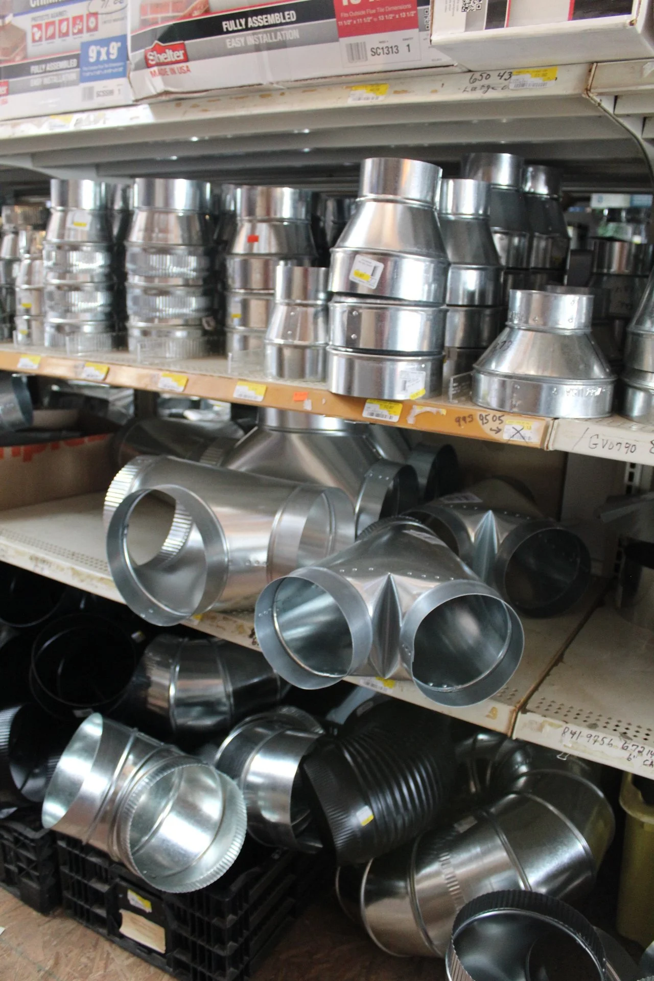 Metal duct elbows and fittings on store shelves, used for HVAC air ventilation systems.