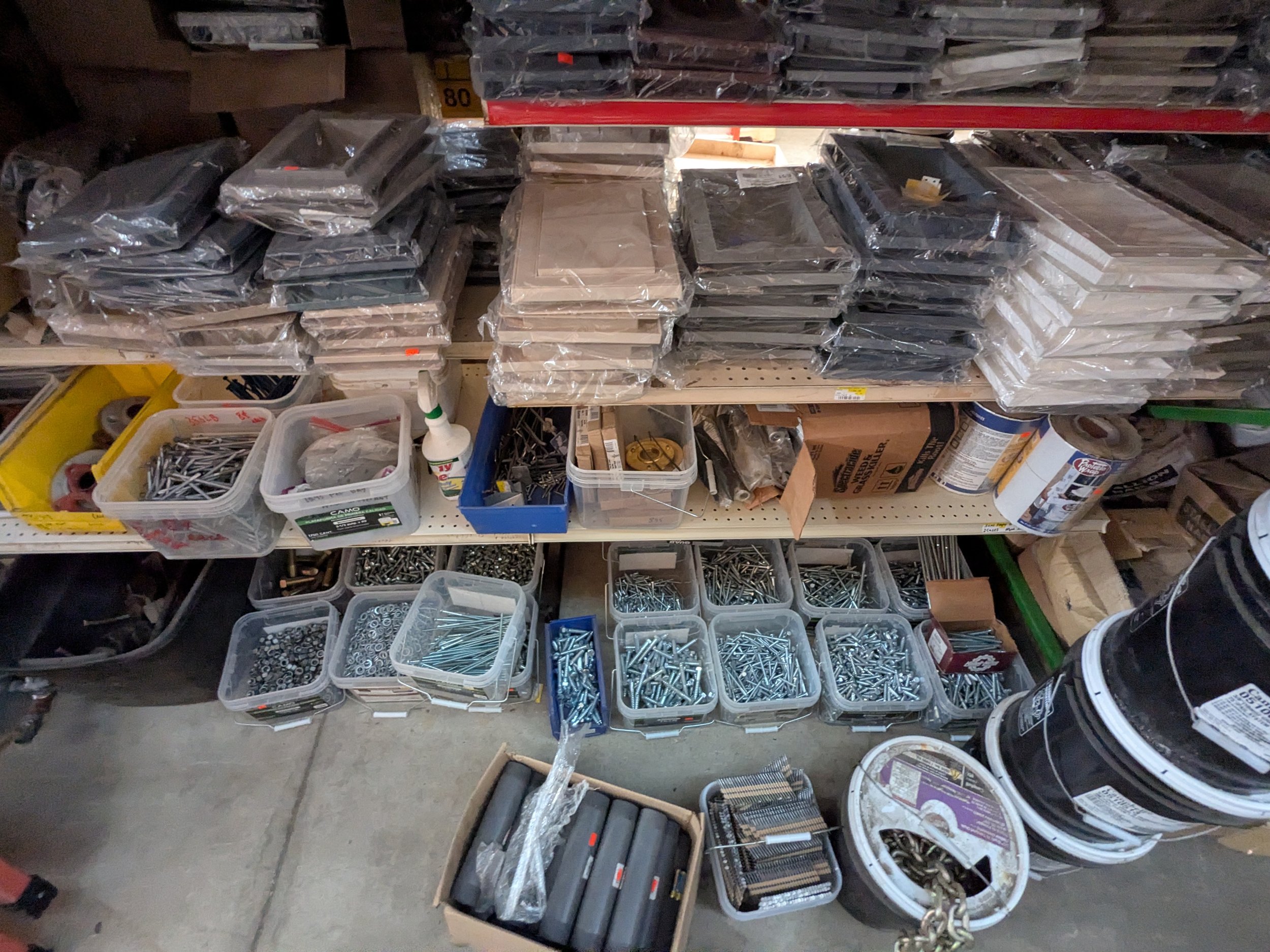 Shelves filled with bags of nails, screws, and hardware supplies in a hardware store or workshop.