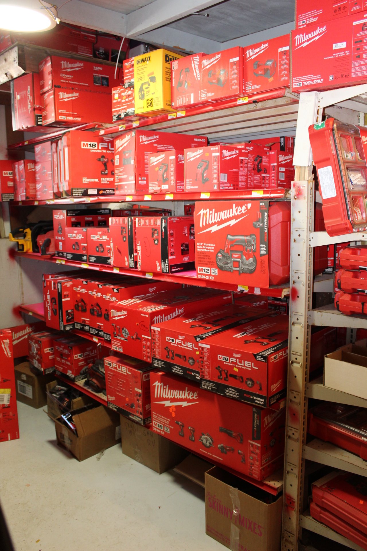 Store shelves displaying Milwaukee and Dewalt power tools and toolboxes in red and yellow packaging.