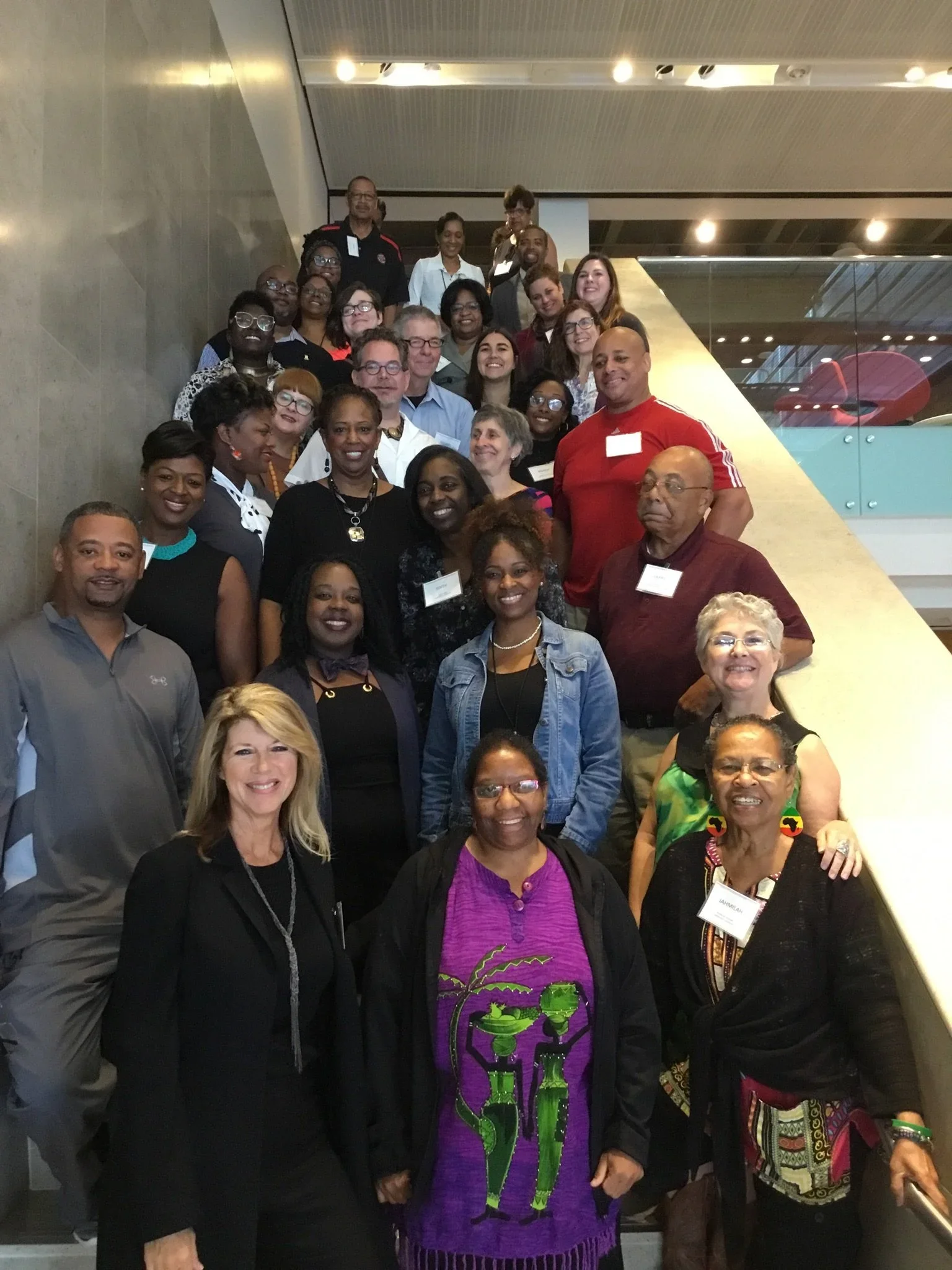 Group of diverse people posing on a staircase indoors, smiling, following NCBI Lafayette training workshop.