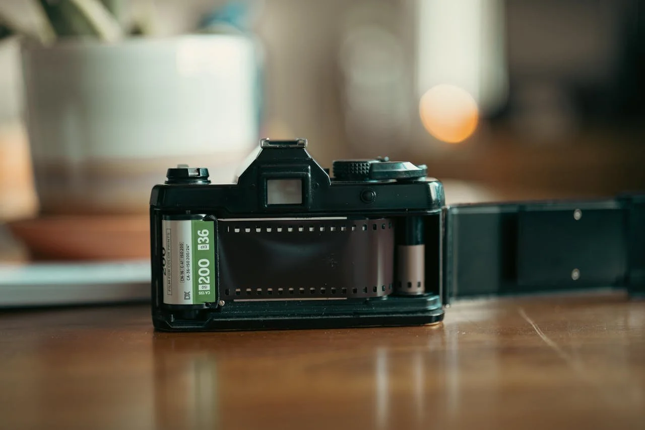 A vintage still camera with its back open, showing a loaded roll of film.