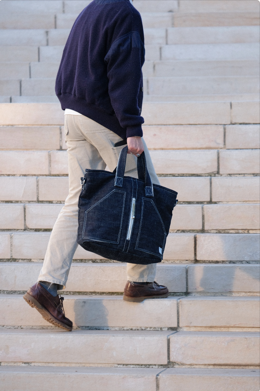 Personnes montant des escaliers en portant un sac en toile noire.