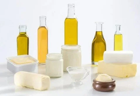 Assorted dairy products including milk bottles, butter, cheese, and cream displayed on a white surface.