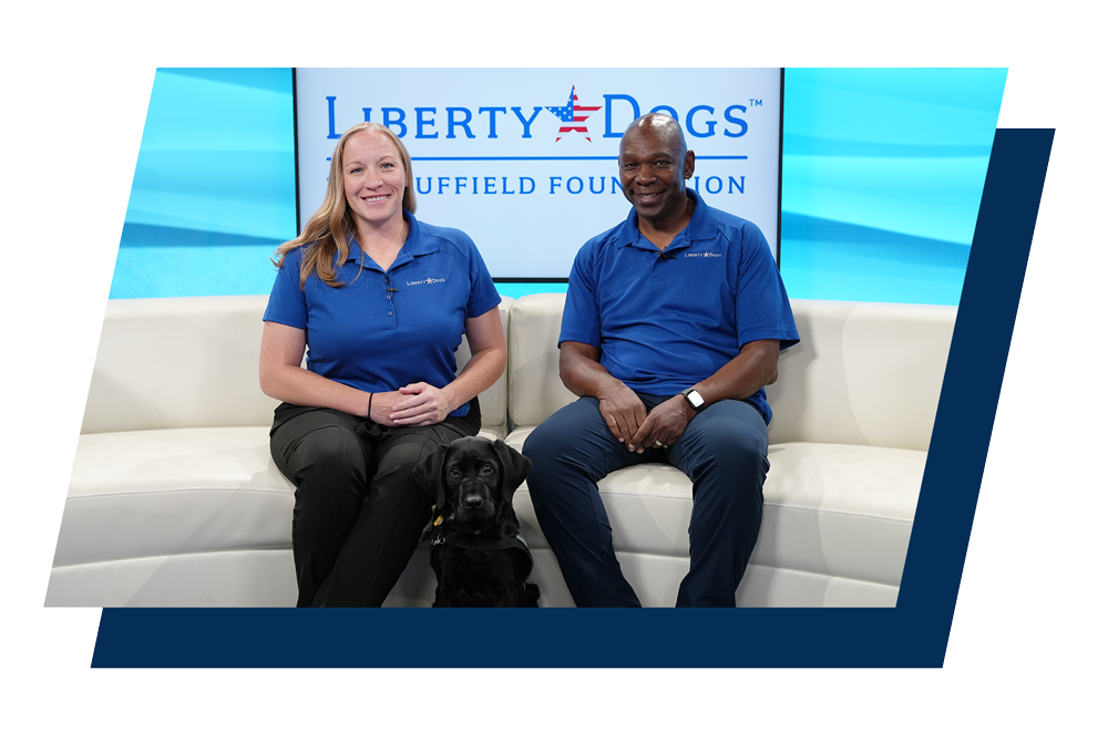 Trainer Hilary Larivee, and CEO Ondra Berry, sit with black labrador retriever, Cooper, on the local news