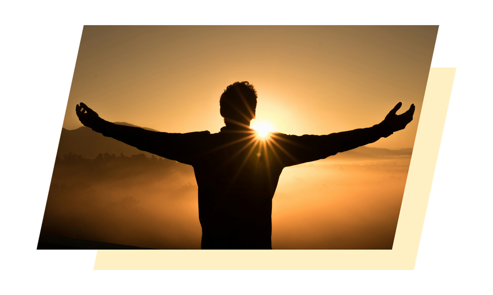 Silhouette of a man spreading his arms out in front of an orange sunset