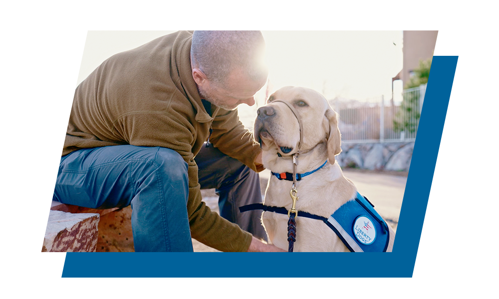 A Veteran sits on a bench while petting his Service Dog