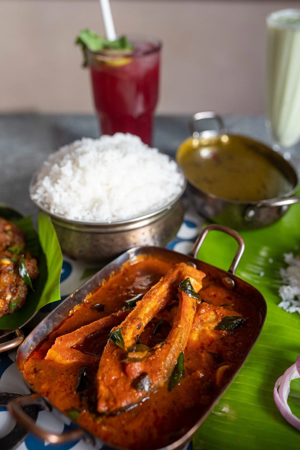 Indian meal with fish curry, white rice, and beverages on a table