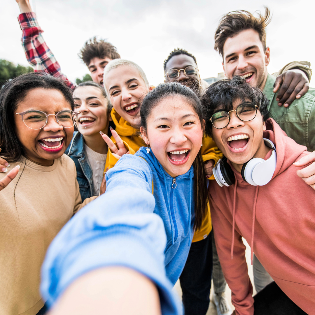 Group of young diverse friends smiling and taking a selfie outdoors.
