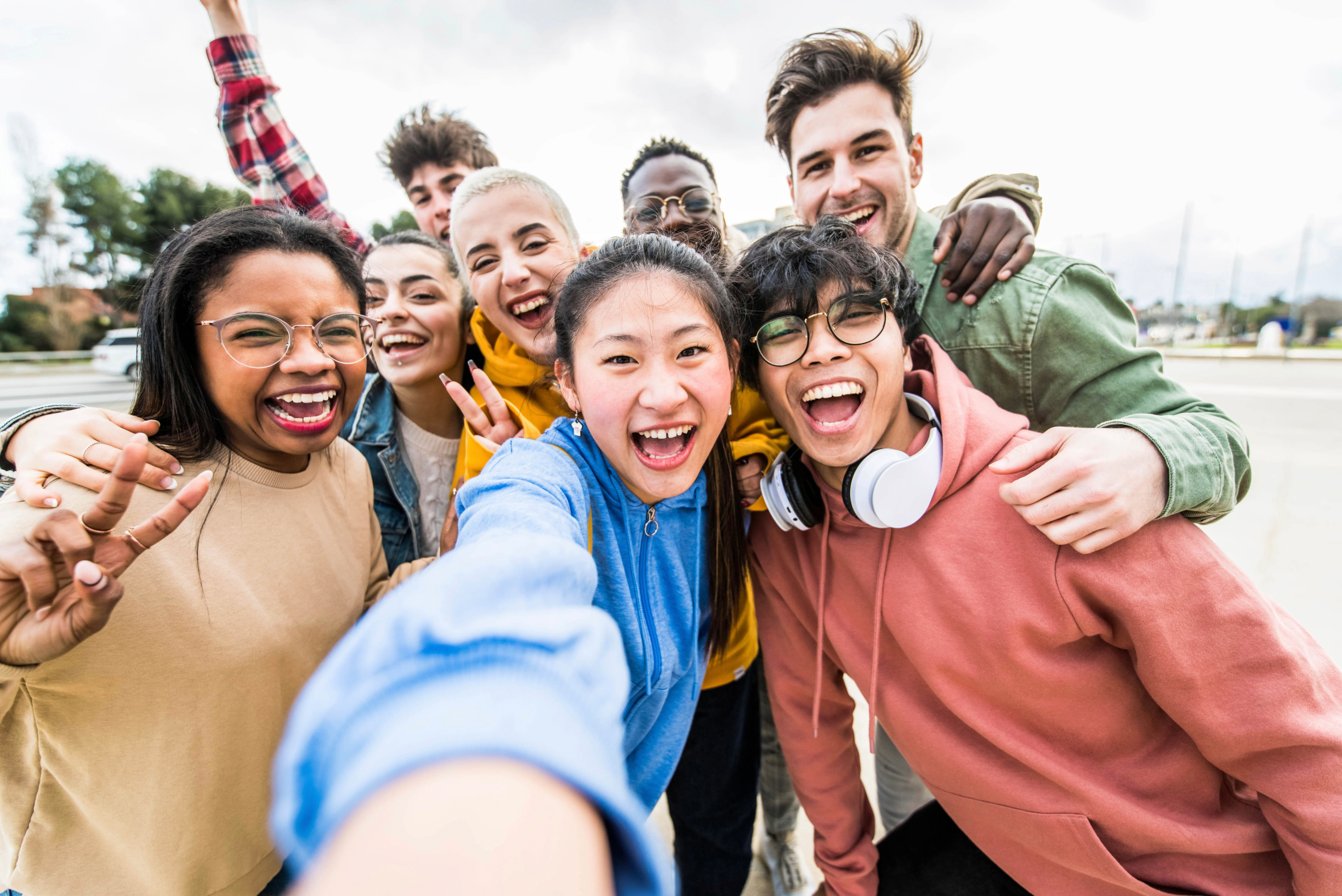 Group of diverse young friends taking a selfie outdoors and smiling